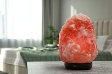 Photo of Beautiful Himalayan salt lamp on light grey table in bedroom, space for text