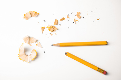 Photo of Broken pencil and shavings on white background, top view