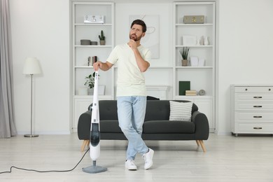 Photo of Thoughtful man with steam mop at home