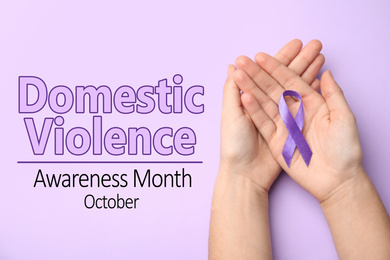 Woman holding purple ribbon on lilac background, top view. Symbol of Domestic Violence Awareness