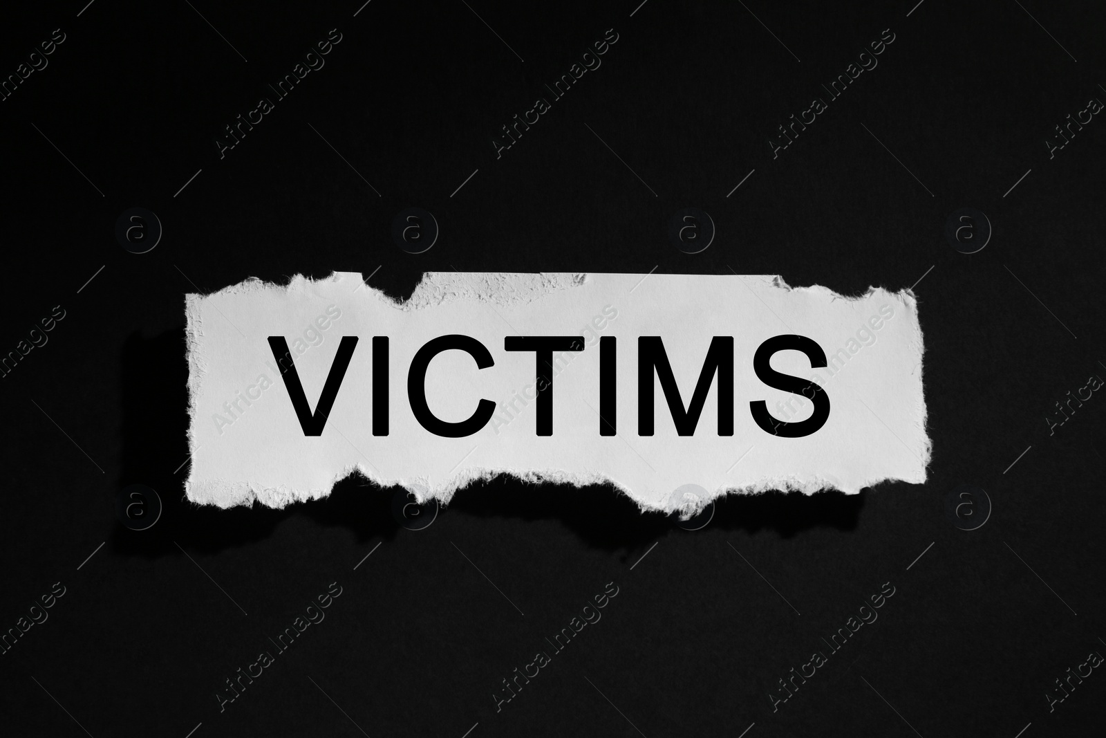 Photo of Paper with word Victims on black background, top view