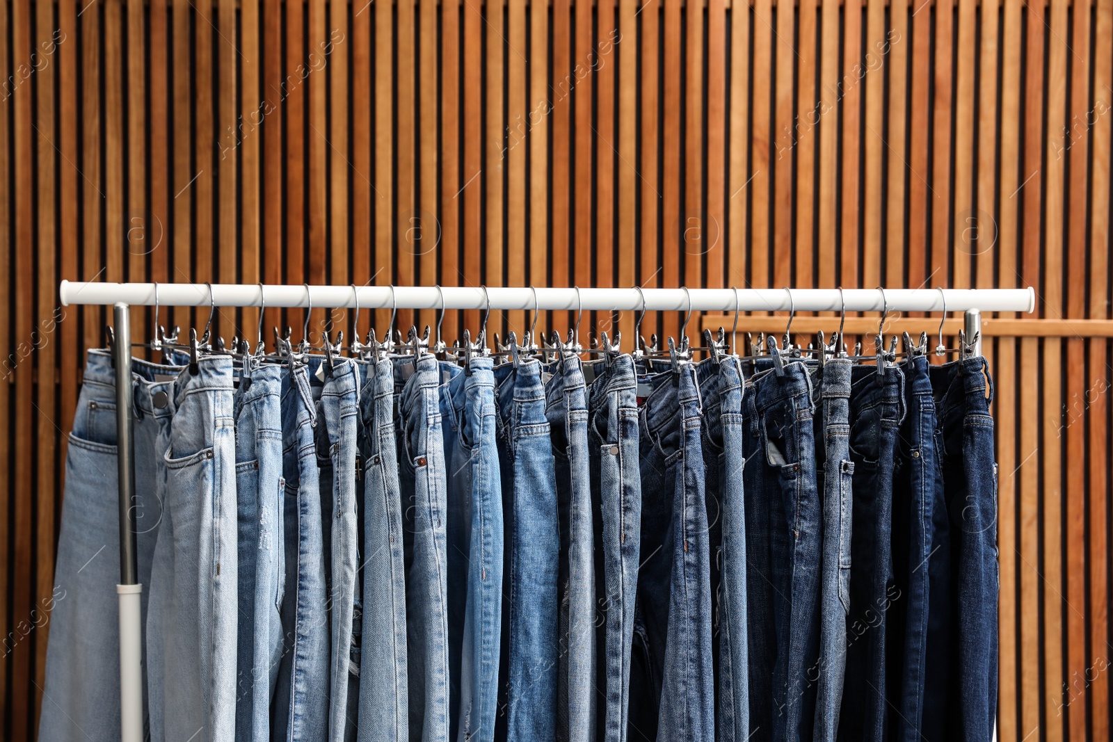 Photo of Rack with different jeans on wooden background