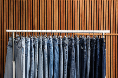 Photo of Rack with different jeans on wooden background