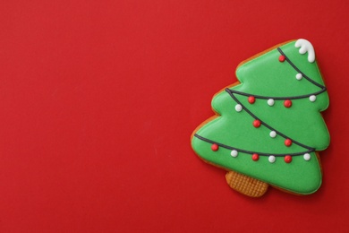 Photo of Christmas tree shaped gingerbread cookie on red background, top view. Space for text