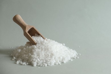 Photo of Organic salt and wooden scoop on light grey background. Space for text