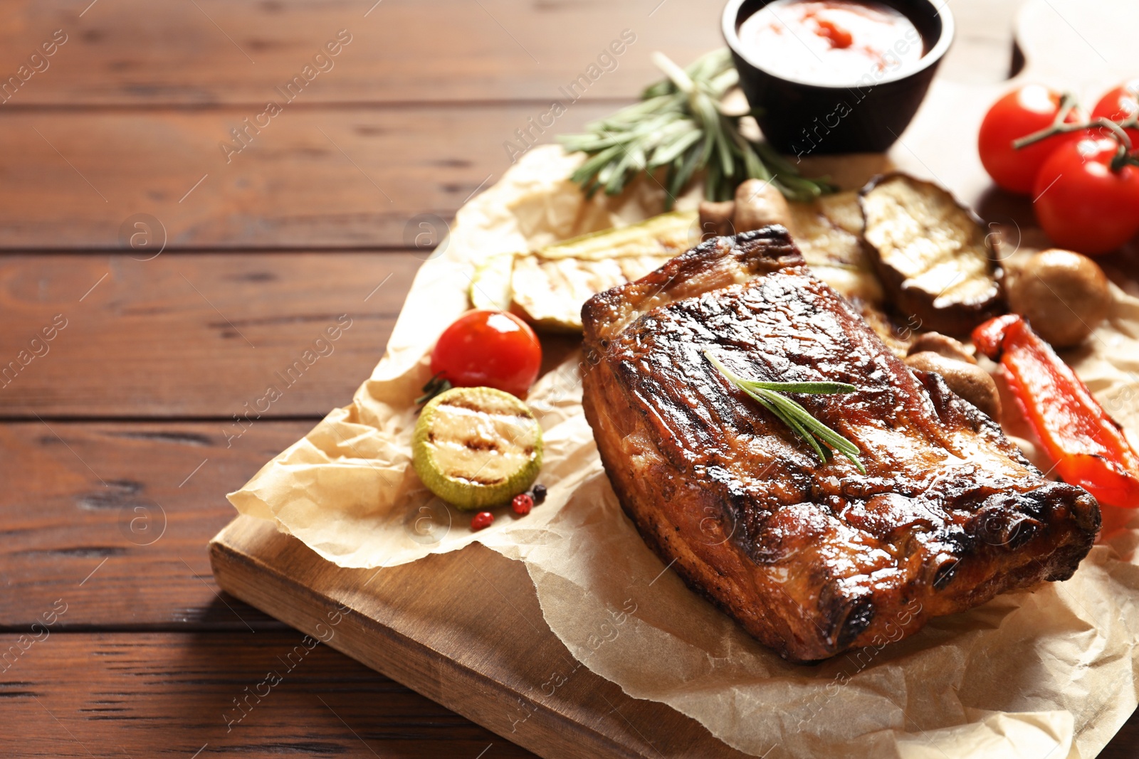 Photo of Delicious barbecued ribs served with vegetables on wooden table. Space for text