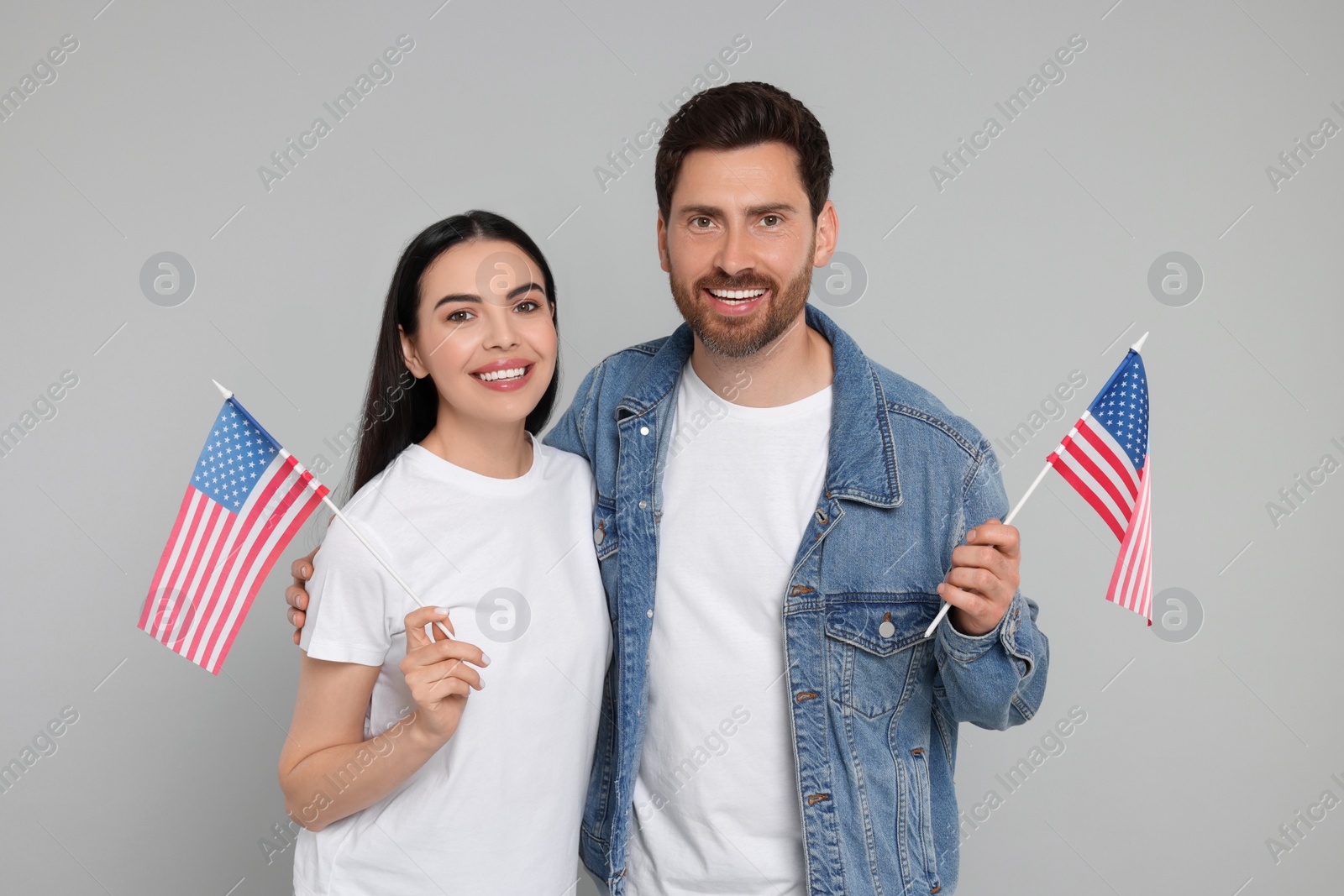 Photo of 4th of July - Independence Day of USA. Happy couple with American flags on grey background