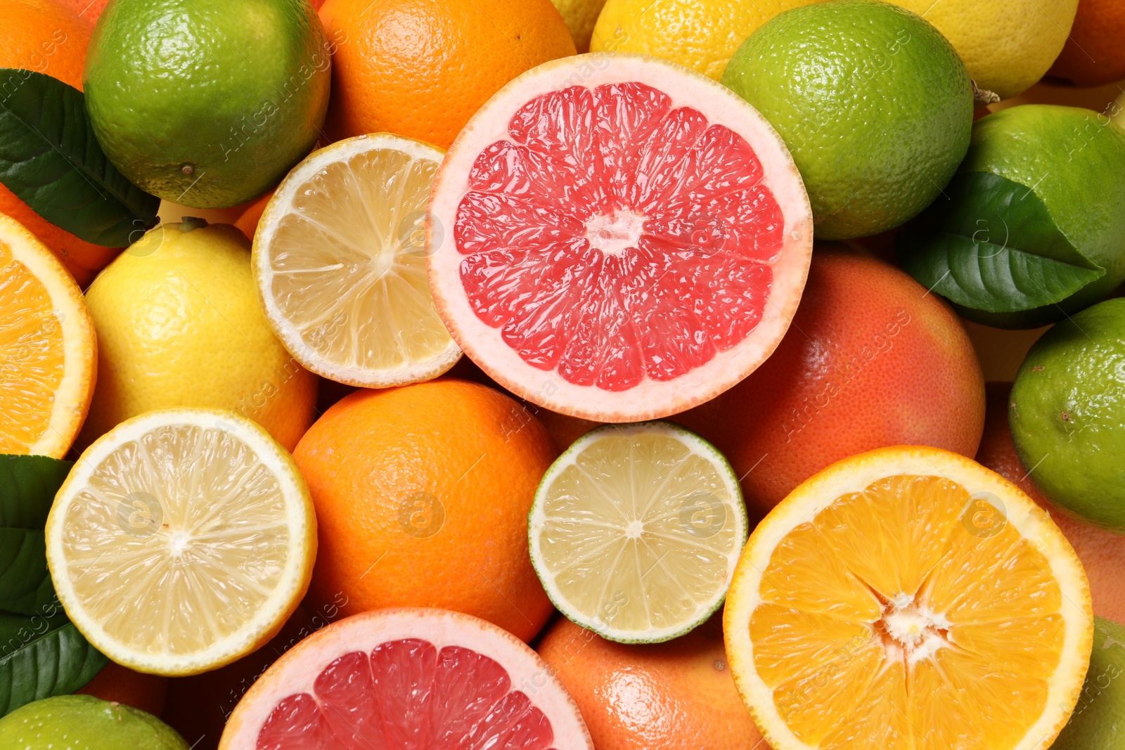 Photo of Different fresh citrus fruits and leaves as background, top view