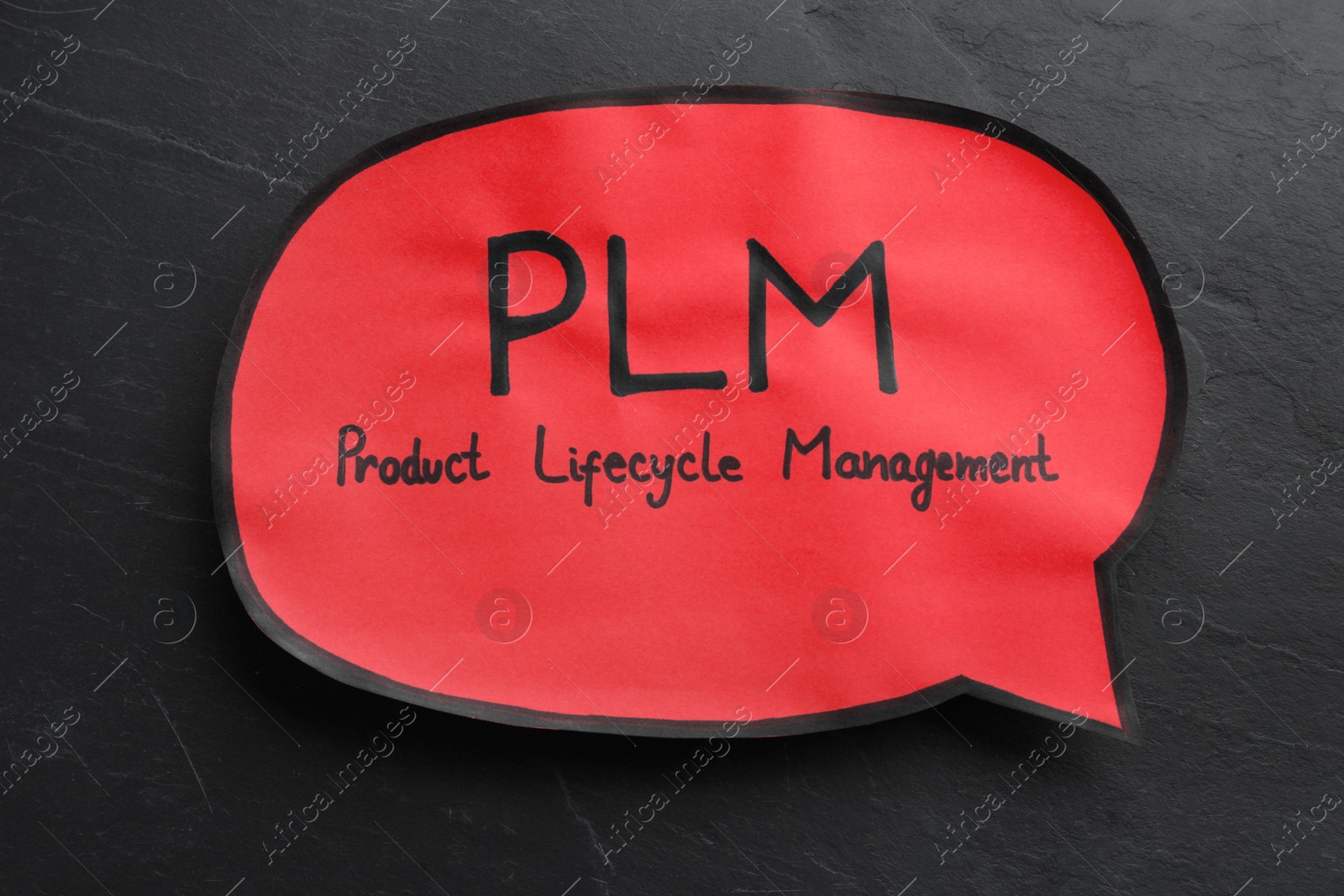 Photo of Paper speech bubble with abbreviation PLM (Product Lifecycle Management) on black slate background, top view