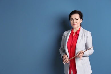 Portrait of female teacher with pointer on color background