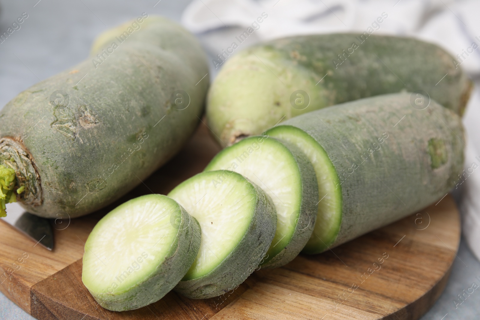 Photo of Green daikon radishes on light grey table, closeup