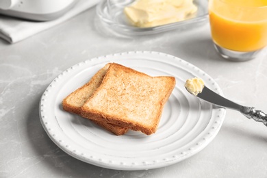 Plate with toasted bread and glass of juice on table