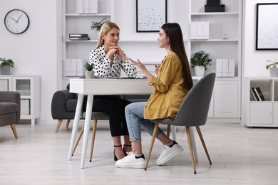 Psychologist working with teenage girl at table in office