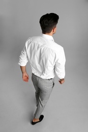 Businessman in formal clothes on grey background, back view