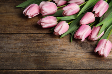 Photo of Beautiful pink spring tulips on wooden background. Space for text