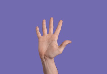 Photo of Man giving high five on purple background, closeup of hand