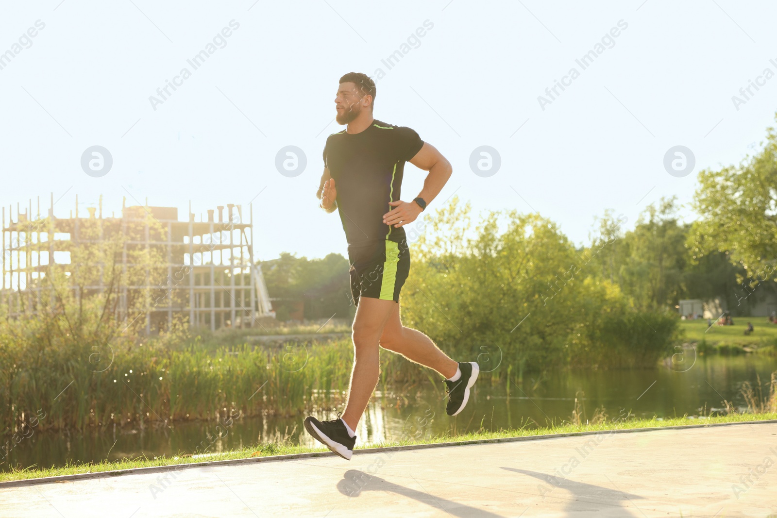 Photo of Young man running near pond in park