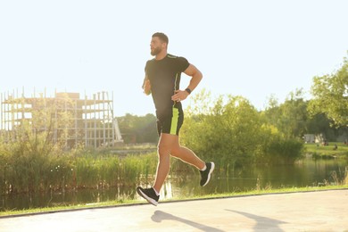 Young man running near pond in park