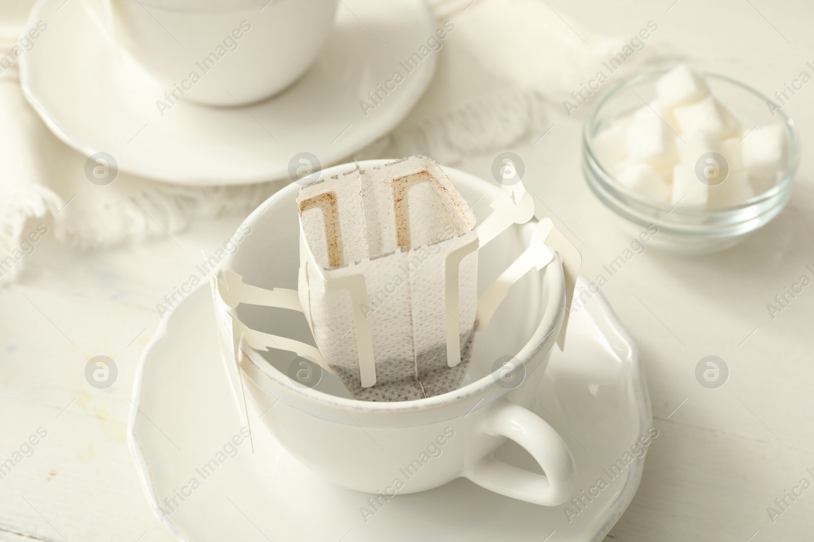 Photo of Cup with drip coffee bag on white table, closeup