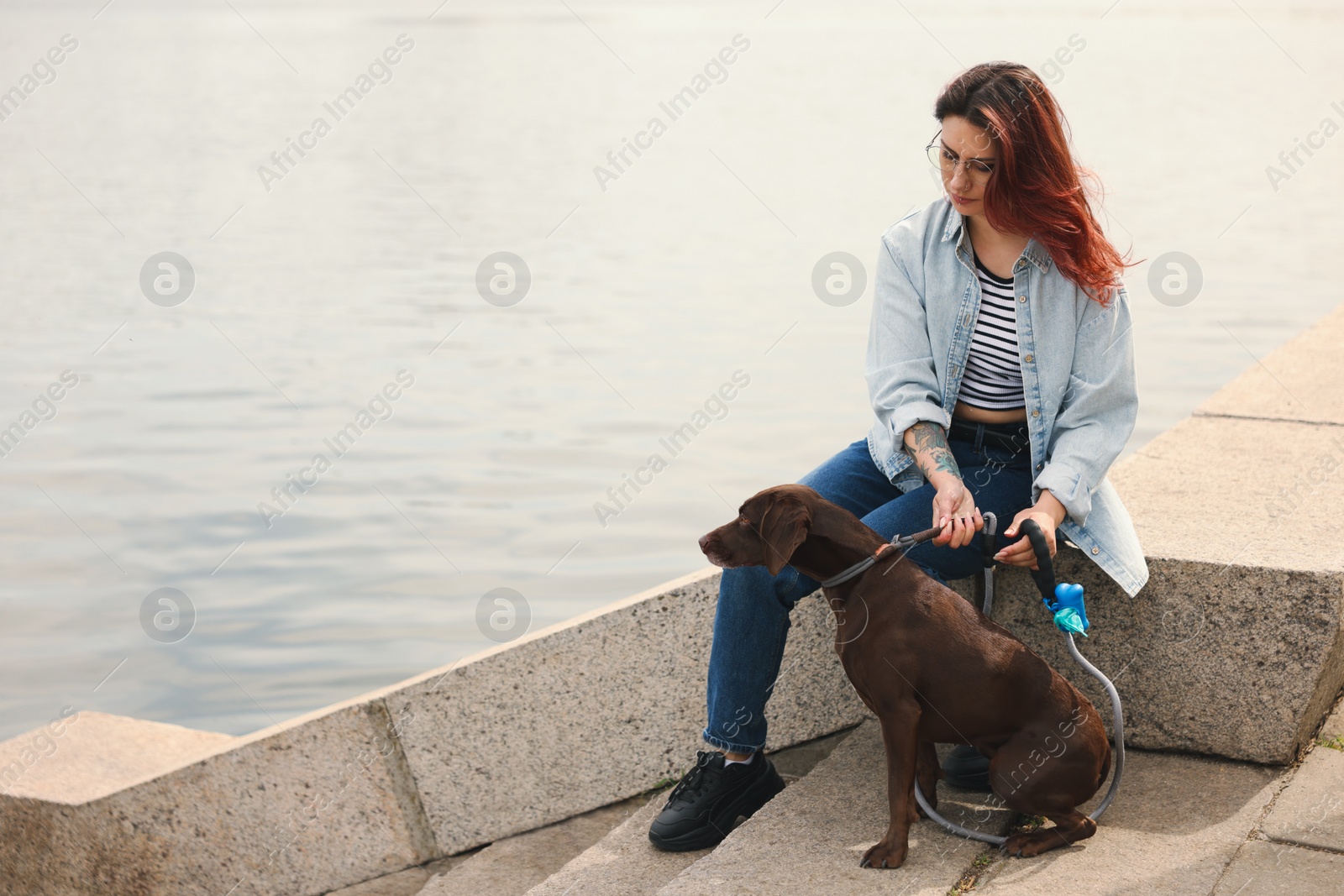 Photo of Woman with her cute German Shorthaired Pointer dog outdoors, space for text