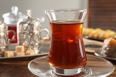 Photo of Traditional Turkish tea in glass on wooden table, closeup