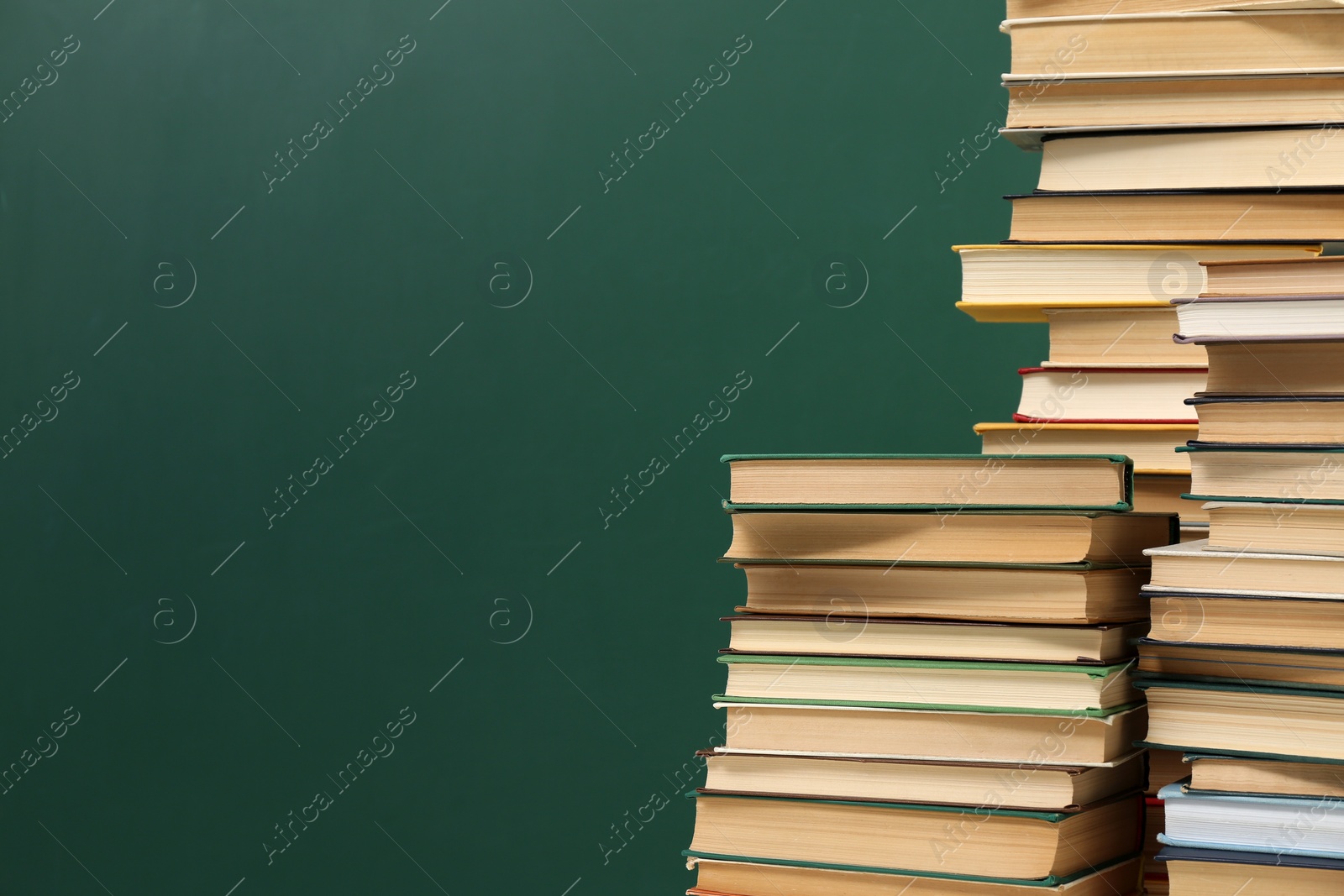 Photo of Many hardcover books near green chalkboard, space for text. Library material