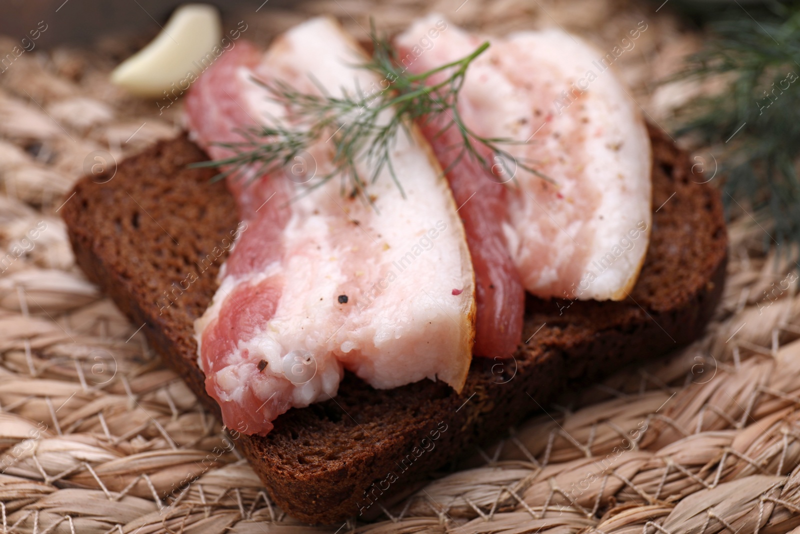 Photo of Sandwich with pork fatback on wicker mat, closeup