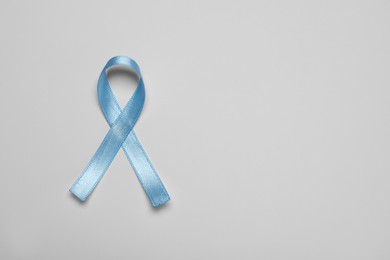 Photo of Light blue awareness ribbon on color background, top view. Space for text