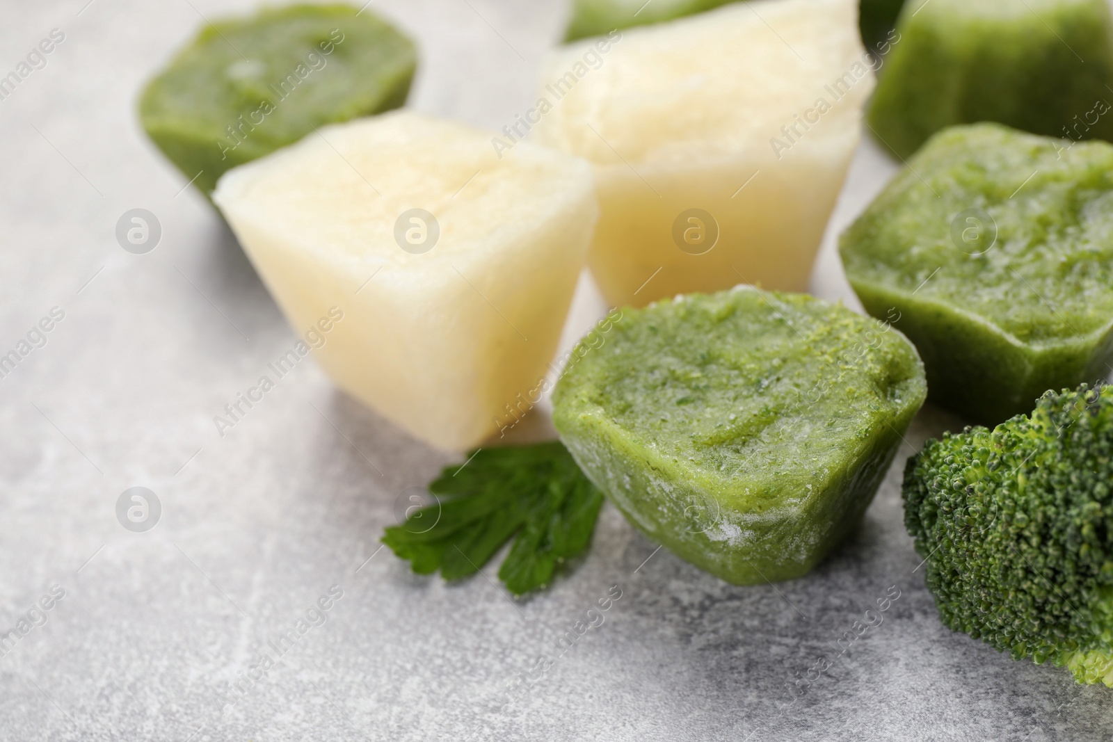 Photo of Frozen cauliflower and broccoli puree cubes on light grey table, closeup