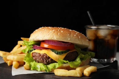 Photo of Delicious burger, soda drink and french fries served on board, closeup