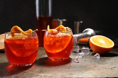 Photo of Aperol spritz cocktail, ice cubes and orange slices in glasses on grey textured table