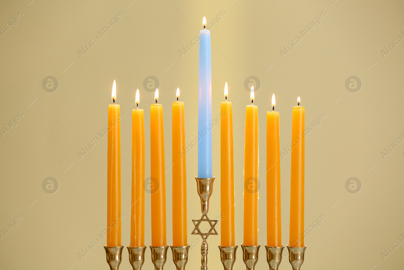 Photo of Hanukkah celebration. Menorah with burning candles on beige background, closeup