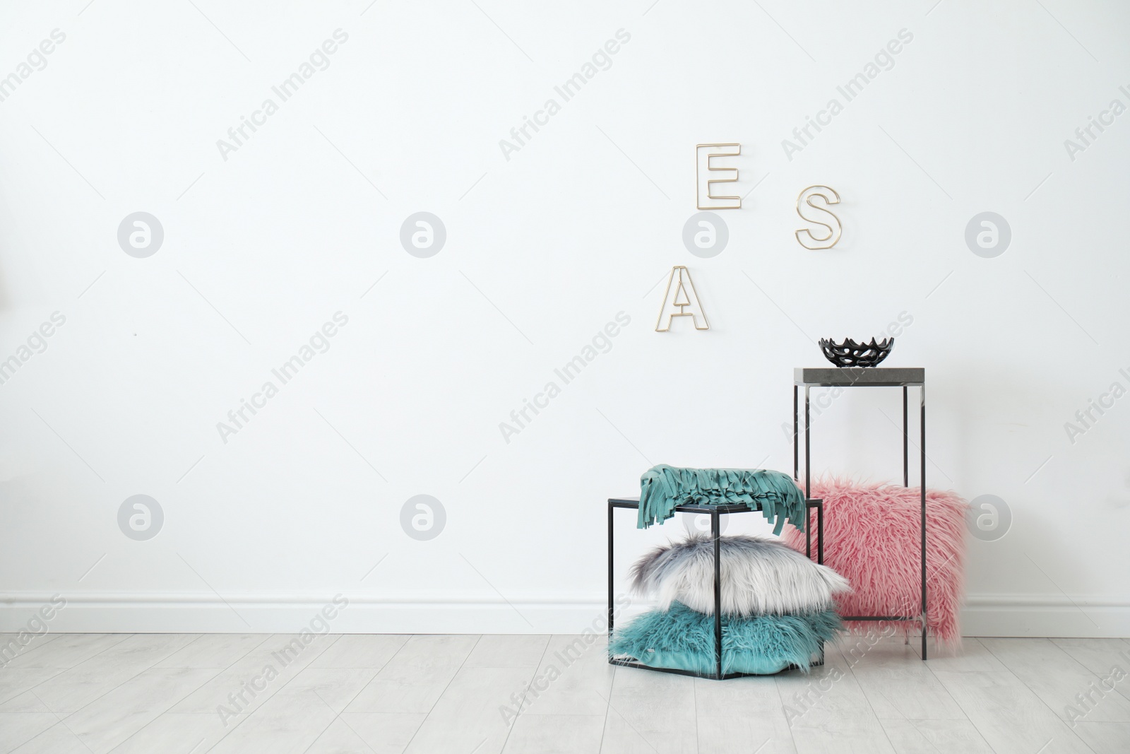 Photo of Tables with pillows near white wall in room