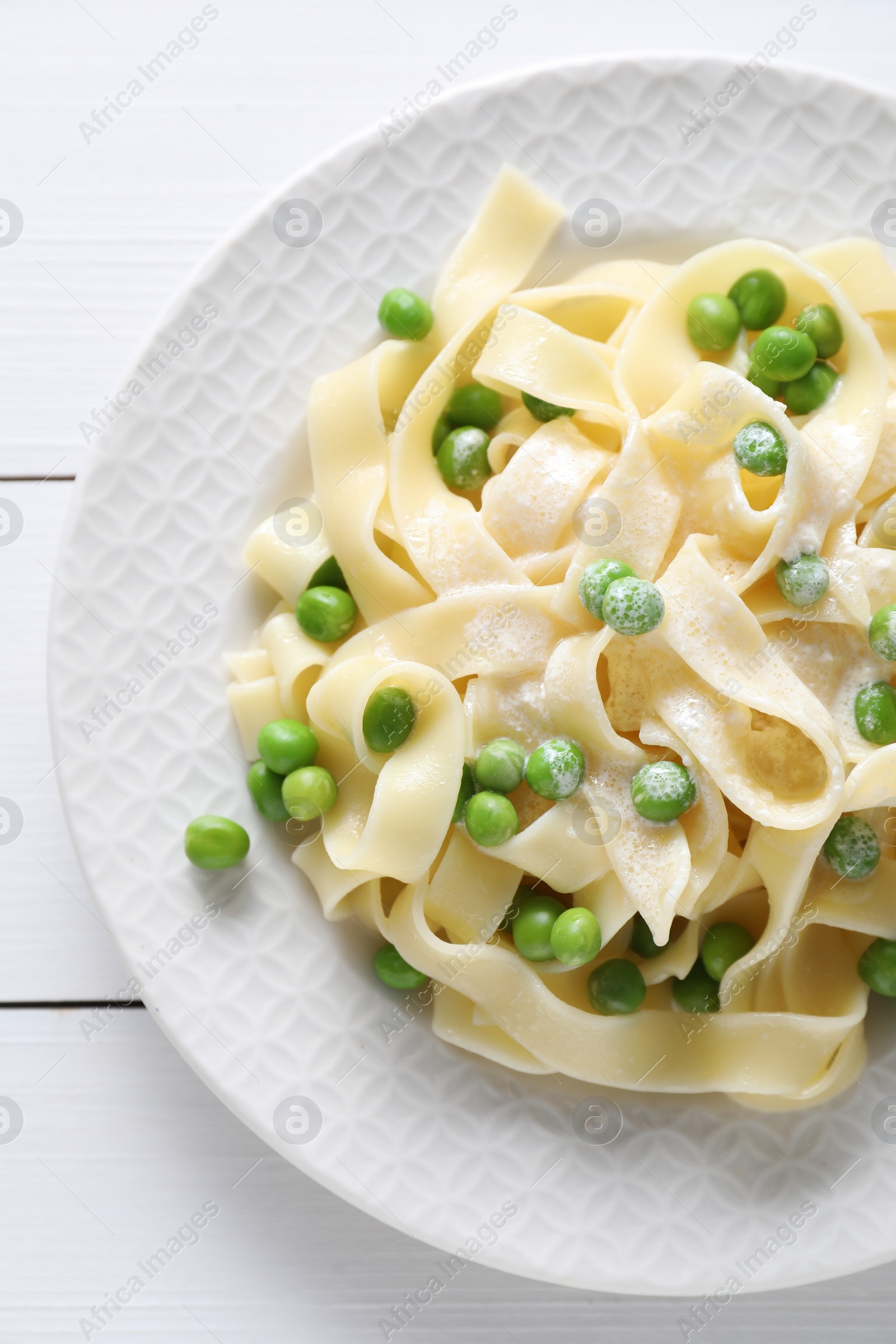 Photo of Delicious pasta with green peas on white wooden table, top view