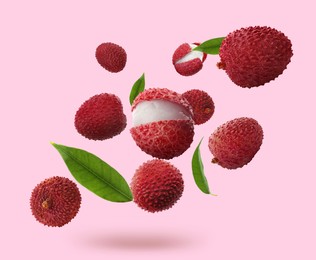 Image of Fresh lychees with green leaves falling on pink background