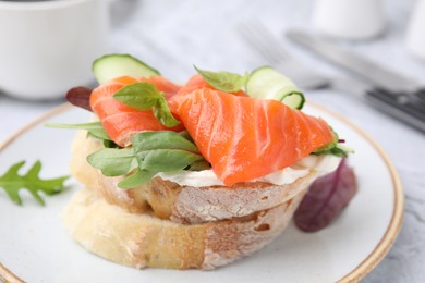 Photo of Tasty bruschetta with salmon, cucumbers and herbs on plate, closeup