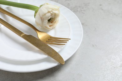 Photo of Stylish table setting with cutlery and flower on grey background, closeup. Space for text
