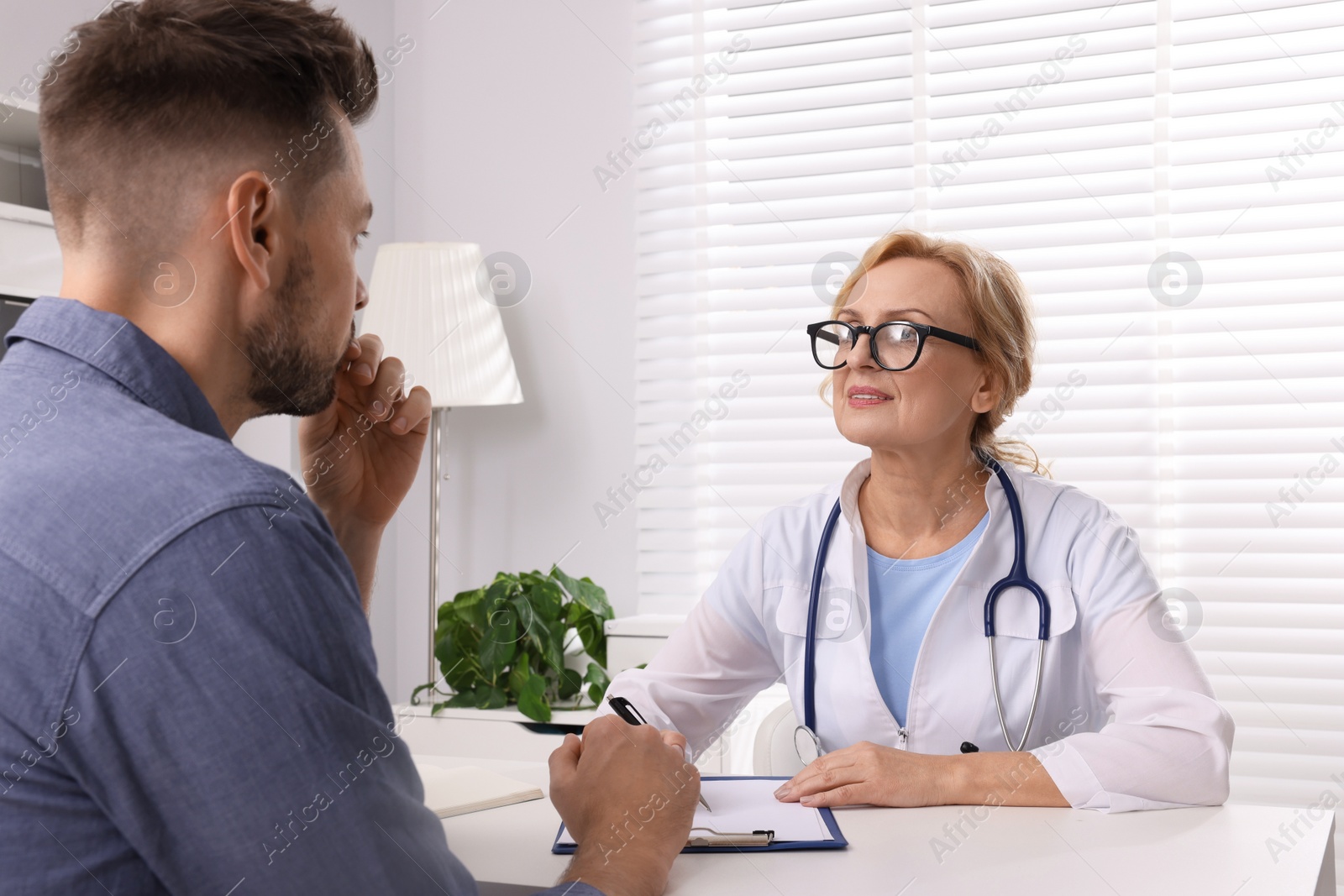 Photo of Doctor consulting patient at table in clinic