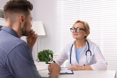 Photo of Doctor consulting patient at table in clinic