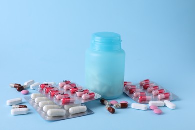 Photo of Different antidepressants with emoticons and medical jar on light blue background