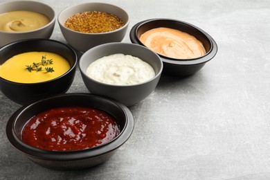 Photo of Many different sauces on grey table, space for text