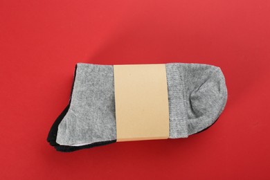 Photo of Soft cotton socks on red background, top view