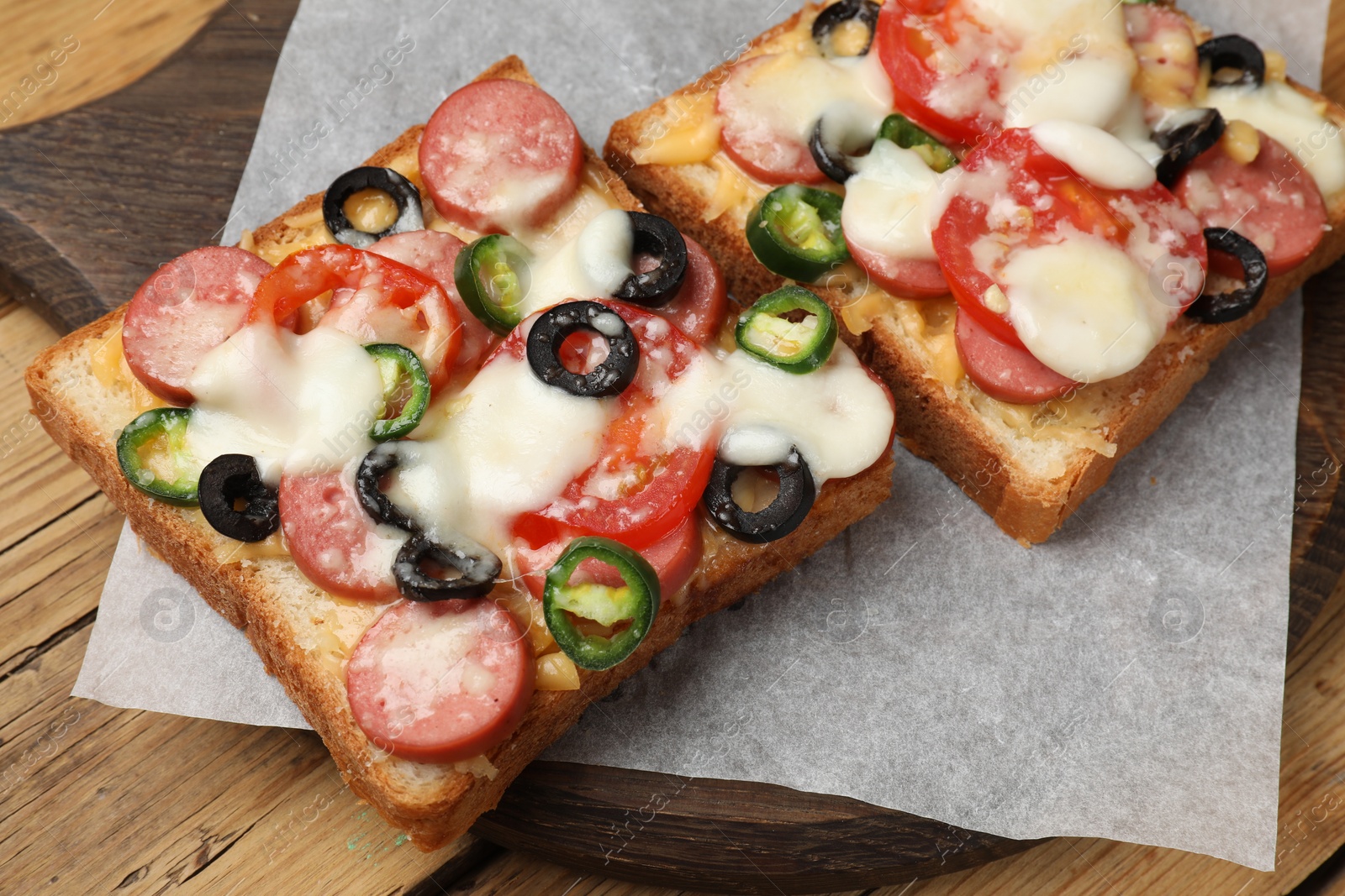 Photo of Tasty pizza toasts on wooden table, closeup