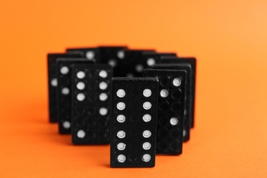 Photo of Black domino tiles with white pips on orange background