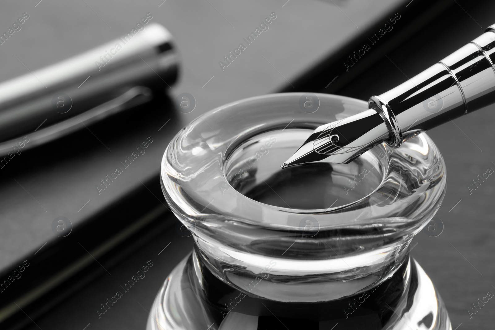 Photo of Inkwell with fountain pen on grey table, closeup