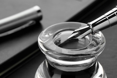 Inkwell with fountain pen on grey table, closeup