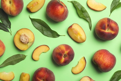 Flat lay composition with sweet juicy peaches on green background