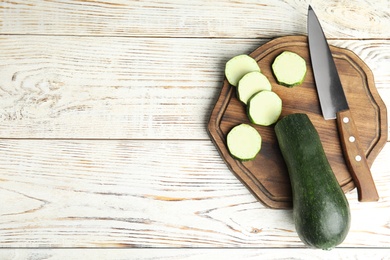 Photo of Fresh ripe green zucchini on white wooden table, top view. Space for text
