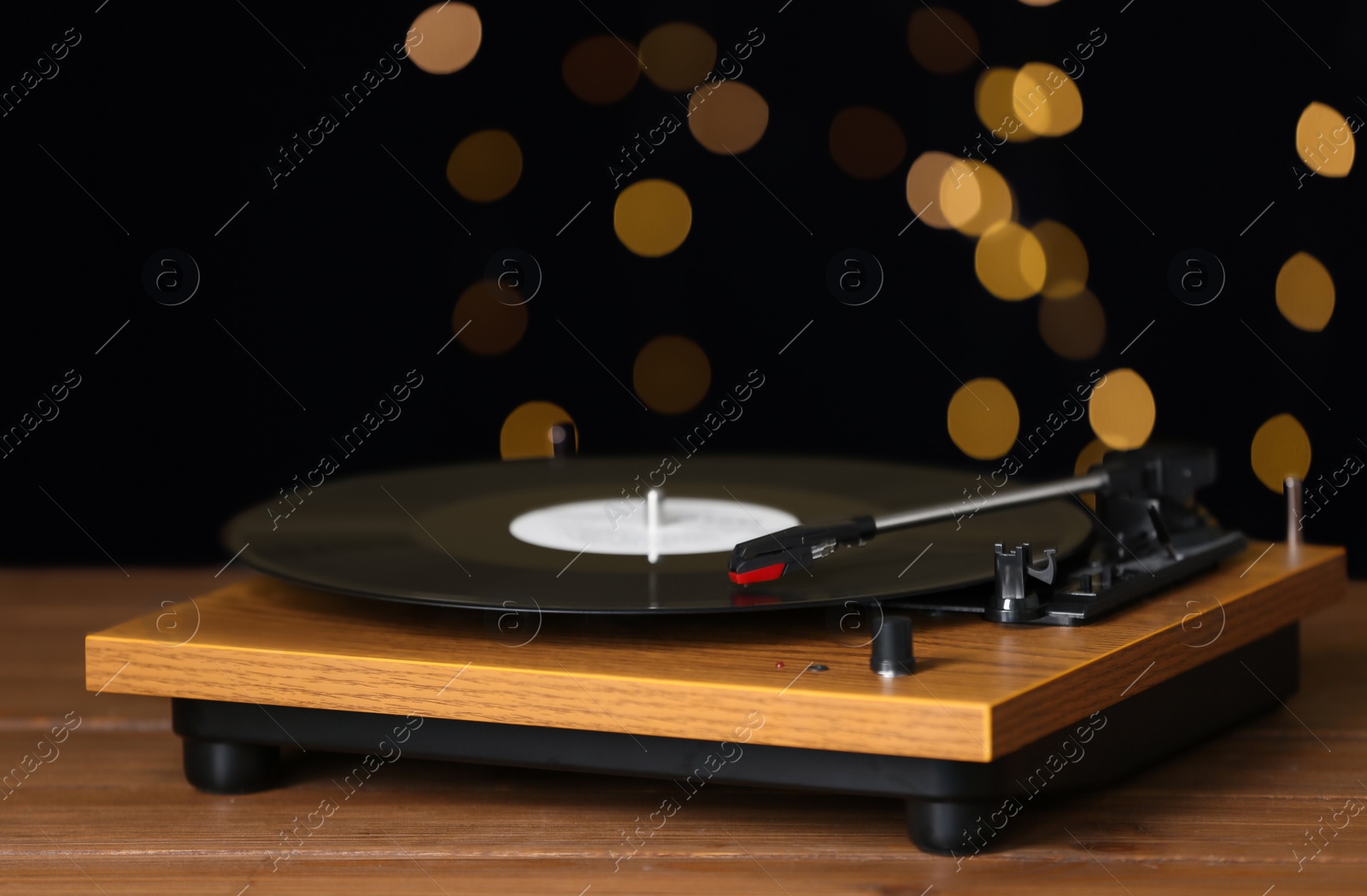 Photo of Turntable with vinyl record against blurred lights. Space for text