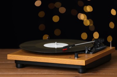 Turntable with vinyl record against blurred lights. Space for text